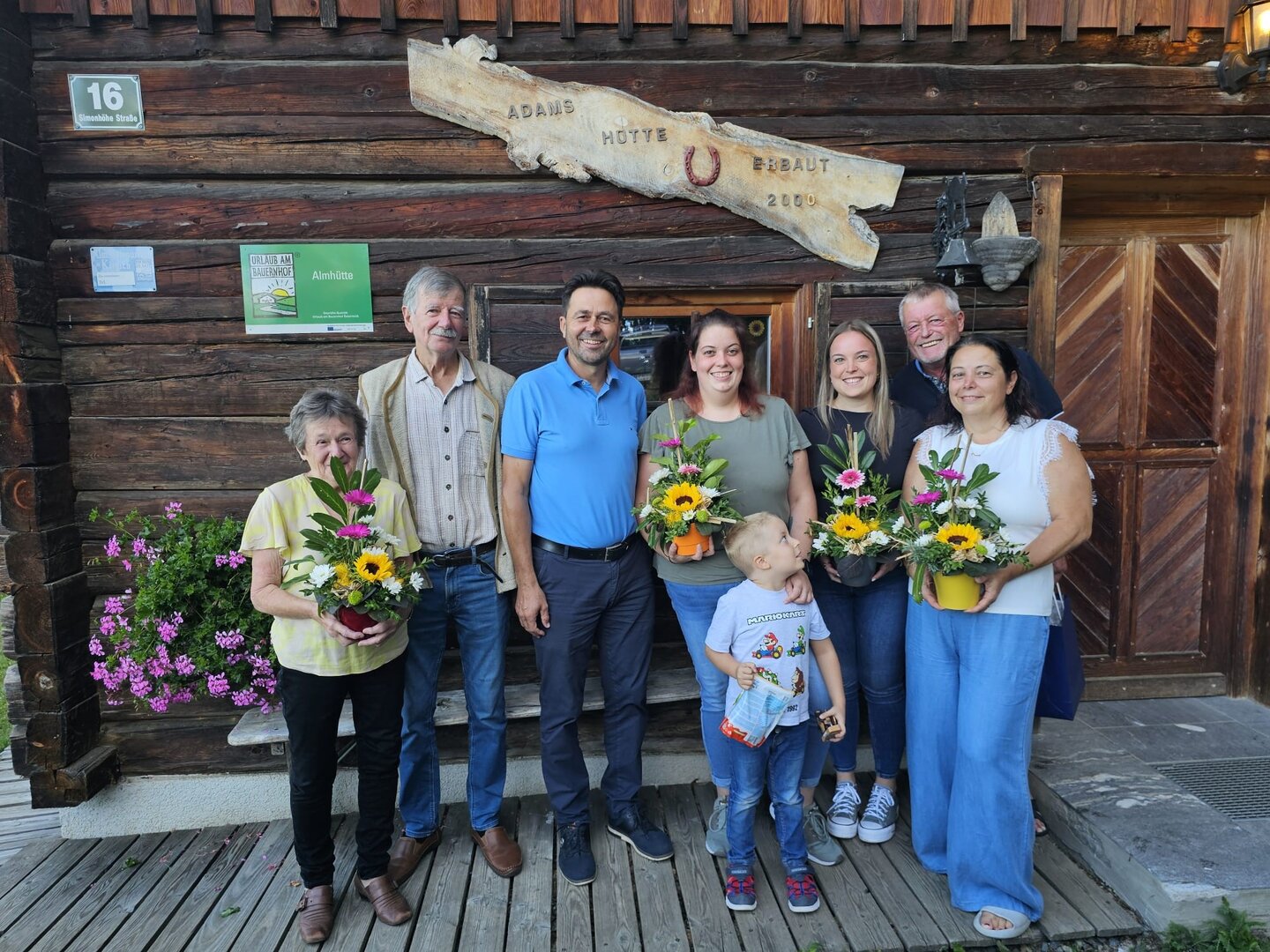 Familie feiert vor Adams Hütte in Tirol mit Blumensträußen